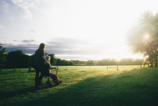 woman standing next to woman riding wheelchair by Dominik Lange courtesy of Unsplash.